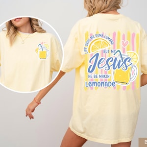 May include: Butter yellow t-shirt with a lemonade graphic on the front and back. The front features a lemonade jar illustration. The back has the text "Life gave me some lemons but my Jesus he be makin' lemonade."
