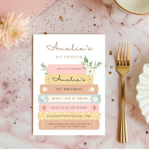 Op de afbeelding: Een roze en gele uitnodigingskaart met een stapel boeken versierd met bloemen. De tekst op de kaart luidt "Amelia's 1st Chapter", "Amelia's 1st Birthday", "Sunday, June 19, 2:00 PM", "123 Any St. Any City, ST 12345", "RSVP by June 30th at (123) 456-7890", en "Please bring a book, let's share the fun as we cheer for Chapter One!"