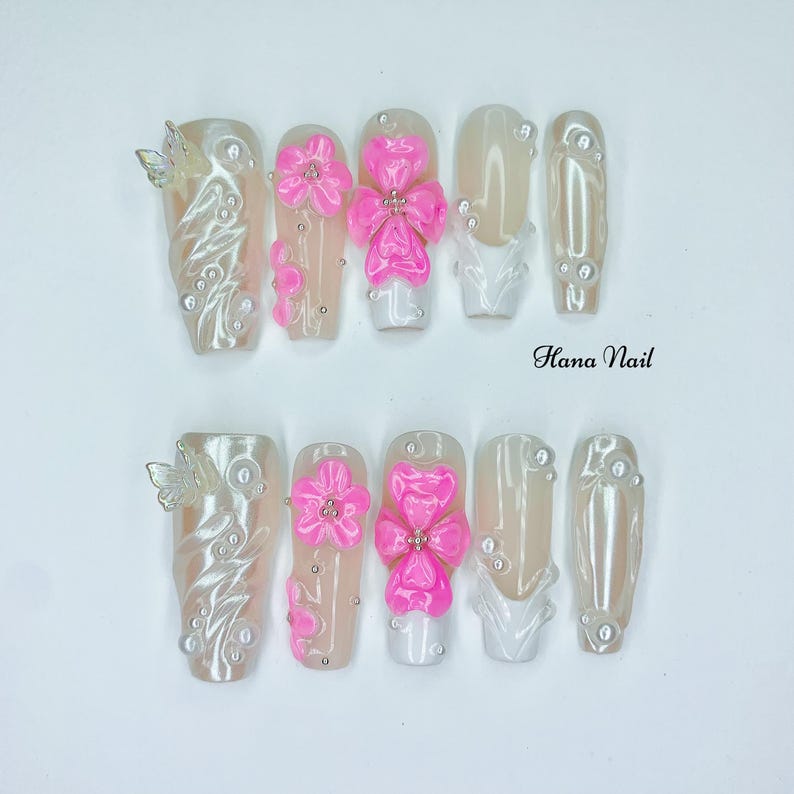 Puede incluir: Un conjunto de diez u&ntilde;as artificiales con diversos dise&ntilde;os. Algunas u&ntilde;as presentan un acabado nacarado con detalles plateados y acentos de mariposa. Otras muestran dise&ntilde;os de flores y lazos rosas brillantes. El texto "Hana Nail" es visible.