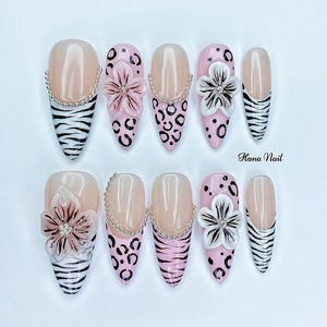 May include: A collection of ten artificial nails with diverse designs. Some nails have a nude base with a zebra print, while others display pink leopard spots, floral decorations, and a silver chain. The text "Hana Nail" is visible.
