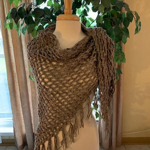 May include: A brown crocheted shawl with fringe on the bottom edge. The shawl is draped over a white mannequin.