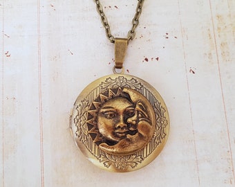 May include: A gold-toned necklace with a locket featuring an embossed design of the sun and moon. The locket is detailed with floral accents.