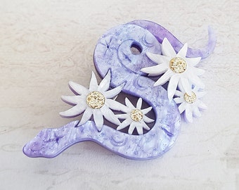 Brosche mit Schlangen- und Blumenmuster, violett, perlmuttfarben, aus schimmerndem Acryl, lilafarbene Schlange und weiße Edelweißblüten, Brosche mit 3D-Prägung