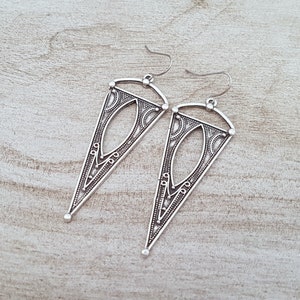 May include: A pair of silver triangle-shaped earrings with intricate geometric designs.