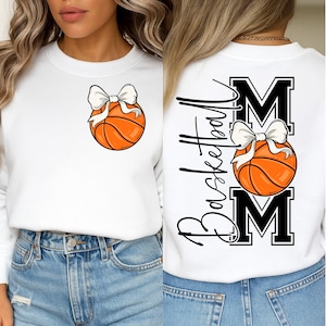 May include: White sweatshirt featuring a basketball with a white bow. The back of the sweatshirt has the word "Basketball" in script, the word "MOM" in block letters, and another basketball with a bow.