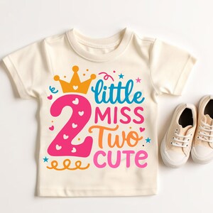 May include: A white t-shirt with a pink number two, a yellow crown, and the text "little miss two cute" in colorful letters.