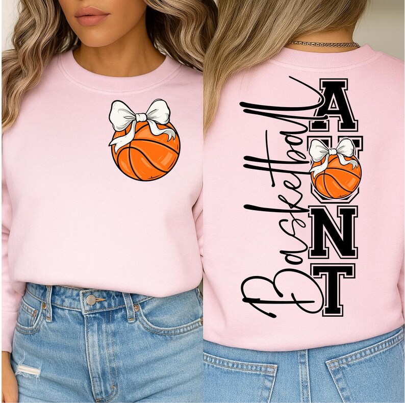 Op de afbeelding: Lichtroze sweatshirt met een basketbal en witte strik. De achterkant toont het woord "Basketball" in zwart script en het woord "Aunt" in blokletters.