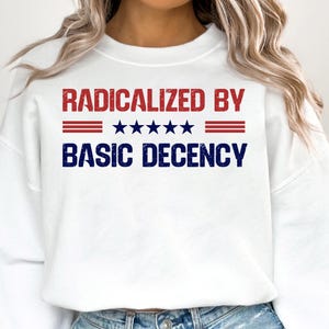 May include: White sweatshirt with red and blue text that reads "Radicalized by" with five stars and three red stripes, and "Basic Decency" in blue text.