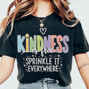 以下が含まれることがあります： 「KINDNESS is free」の文字がカラフルなブロック体で書かれた黒いTシャツ。白いハートと「SPRINKLE IT EVERYWHERE」の文字も。ヴィンテージ感のあるウォッシュ加工が施されています。