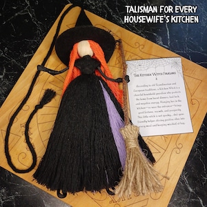 Puede incluir: Una muñeca bruja de cocina con cabello de lana naranja, sombrero negro y vestido negro con un acento morado. La muñeca sostiene una pequeña escoba y viene con una tarjeta titulada The Kitchen Witch Folklore y el texto TALISMAN FOR EVERY HOUSEWIFE'S KITCHEN.
