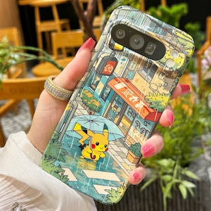 May include: A phone case featuring a colorful illustration of a street scene with a yellow Pikachu character holding an umbrella in the rain. The case has a glossy finish and a detailed design with buildings and shop signs.