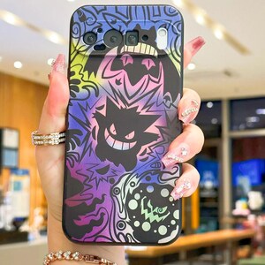 Puede incluir: Funda de tel&eacute;fono negra con un dise&ntilde;o colorido que presenta un personaje de dibujos animados sonriente. La funda tiene un esquema de color p&uacute;rpura, azul, amarillo y verde. Tiene recortes para la c&aacute;mara y otras funciones del tel&eacute;fono.