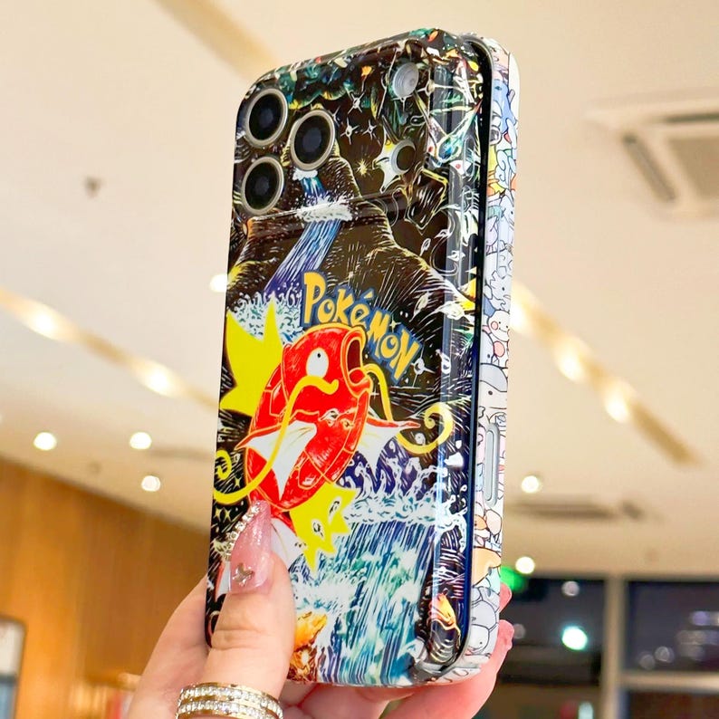 May include: A colorful phone case featuring a vibrant illustration of a red and yellow Pokemon character with the word "Pokemon" in yellow. The case has a waterfall and forest background.