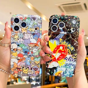 May include: Two phone cases with colorful designs. One case features a collage of cartoon characters. The other case has a red and yellow cartoon character with the text "Poke Mon" over a waterfall scene. Both cases have multiple camera cutouts.