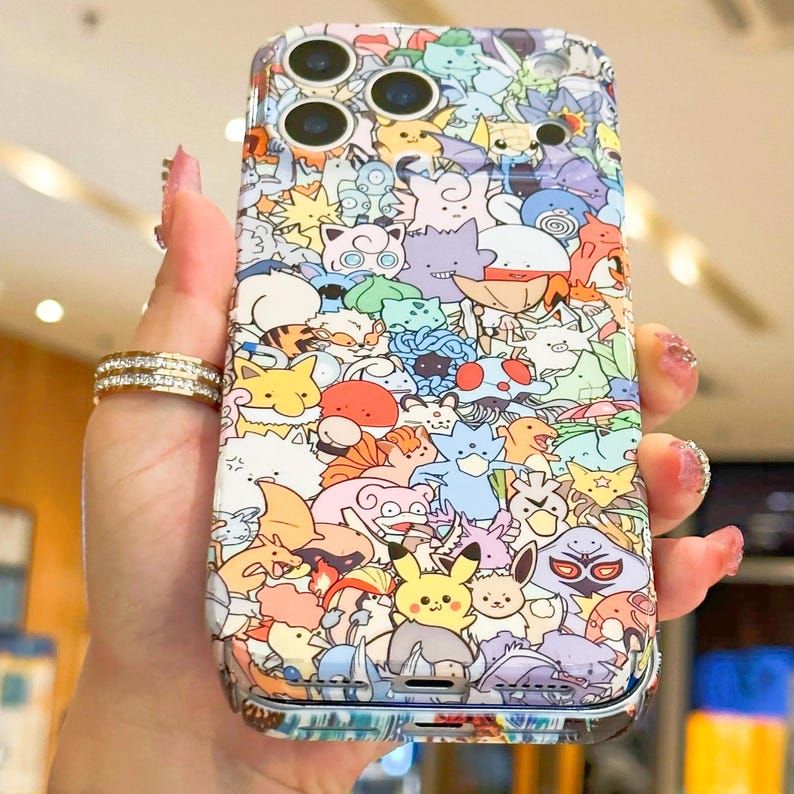 May include: A colorful phone case featuring a vibrant collage of cartoon characters in various colors. The case has a glossy finish and is designed to fit a smartphone. The design includes characters from a popular animated series.