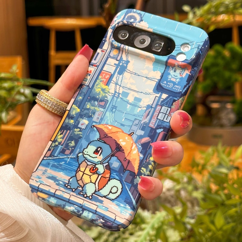 May include: A blue phone case featuring a pixelated illustration of a Squirtle character holding an orange umbrella in a rainy street scene. The case has a light blue top and a camera cutout.
