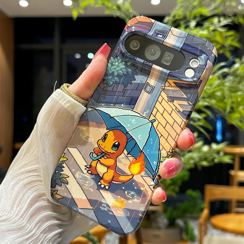 May include: A phone case featuring a cartoon Charmander character holding a blue umbrella in a rainy scene. The case has a pixelated background with brick and roof details. The case is held by a person.