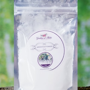 May include: A white resealable pouch containing arrowroot powder. The pouch has a label with the text "Goddess of Herbs" and "Arrowroot Powder" in a purple circle with a floral design. The label also includes the text "1 oz" and a website address.