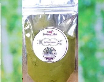 Puede incluir: Una pequeña bolsa de plástico transparente que contiene un polvo verde etiquetado como "Matcha Powder" con un logotipo circular blanco que dice "Goddess of Herbs". El logotipo tiene un pequeño gráfico de flor rosa. La bolsa es de 1 oz.