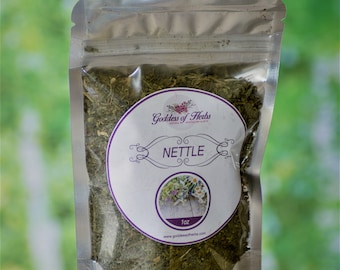 May include: A silver resealable pouch filled with dried green nettle leaves. The pouch has a white label with the text "Goddess of Herbs" and "NETTLE" in purple lettering. The label also includes a small image of a bouquet of flowers and the text "1 oz" and "www.goddessofherbs.com".