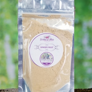 May include: A clear plastic bag with a resealable zipper closure contains a light brown powder. A white round label with purple text and a floral design reads "Goddess of Herbs" and "Ginger Root" with a 1 oz size. The label also includes the website address "www.goddessofherbs.com".
