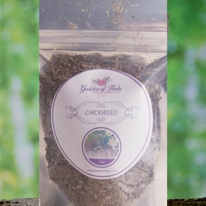 May include: A clear plastic bag filled with dried chickweed, labeled "Goddess of Herbs" with a small image of a plant and the text "Chickweed 1 oz www.goddessofherbs.com"