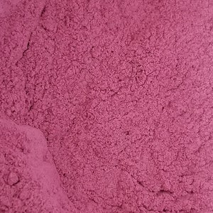 May include: A close-up of a pile of fine, deep pink powder. The powder has a slightly grainy texture and is evenly distributed.