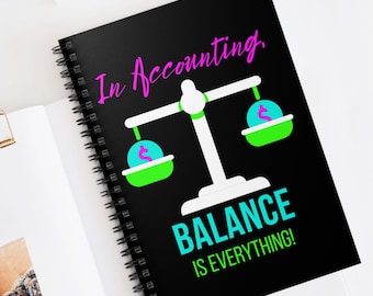 May include: Black spiral-bound notebook with the text "In Accounting" in pink script. The notebook features a balance scale graphic with dollar signs in the pans, and the words "BALANCE IS EVERYTHING!" in teal.