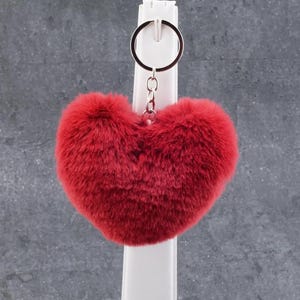 Peut inclure: Un porte-clés en forme de cœur rouge et moelleux avec un anneau de clé argenté.