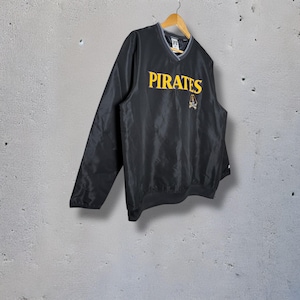 May include: Black pullover jacket with a V-neck collar and long sleeves. The word "PIRATES" is embroidered in yellow across the chest, with a skull and crossbones logo below. The jacket is hanging on a wooden hanger.