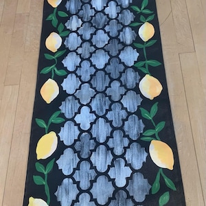 May include: A black and white patterned doormat with a border of yellow lemons and green leaves.