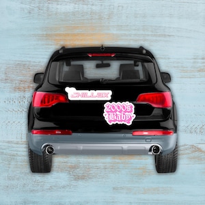 Puede incluir: SUV negro con dos pegatinas rosas en la parte trasera. Una pegatina dice "CHILLAX" en fuente blanca con contorno rosa. La otra pegatina dice "2000's Baby" en fuente rosa cursiva con contorno blanco.