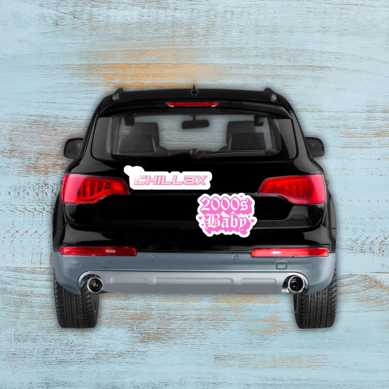Puede incluir: SUV negro con dos pegatinas rosas en la parte trasera. Una pegatina dice "CHILLAX" en fuente blanca con contorno rosa. La otra pegatina dice "2000's Baby" en fuente rosa cursiva con contorno blanco.