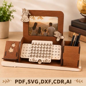 Peut inclure: Un organisateur de bureau en bois avec un cadre photo central affichant une famille, un calendrier perpétuel coulissant à découpes circulaires, un porte-stylo et un petit support latéral. Le bois brun foncé est orné de motifs de cloche et de gland.