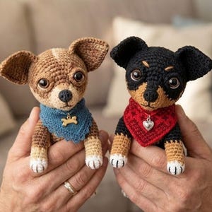 Peut inclure: Deux petites figurines de chien au crochet. Le chien de gauche est marron et blanc avec un bandana bleu et une breloque en forme d'os doré. Le chien de droite est noir et beige avec un bandana rouge et une breloque cœur argentée.