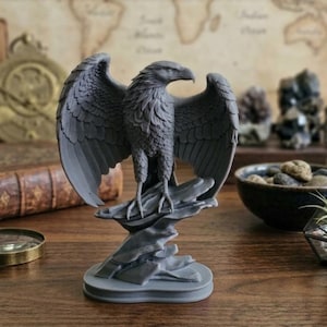 May include: A gray eagle statue with outstretched wings, perched on a rocky base. The detailed sculpture features a realistic depiction of the bird's feathers and beak. The statue is a decorative item, suitable for home decor.