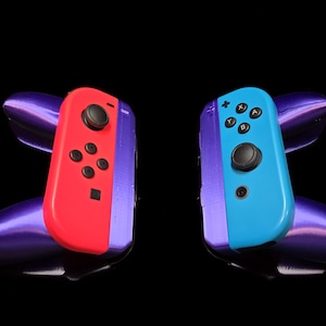 May include: Two Nintendo Switch Joy-Con controllers with purple and blue accents. The left controller is red and the right controller is blue.