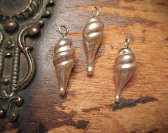 May include: Three vintage glass ornaments in a pear shape with a swirl design. The ornaments are a pale pink color with a silver metallic sheen.