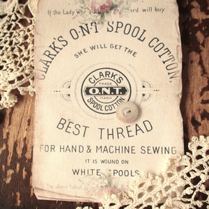 May include: Vintage Clark's O.N.T. Spool Cotton label with a white background and black text. The label reads "Clark's O.N.T. Spool Cotton" and "Best Thread for Hand & Machine Sewing". A white button is attached to the label.
