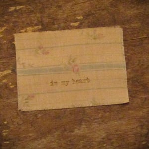 May include: A beige fabric with a floral pattern and the text "in my heart" printed on it.