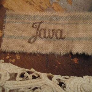May include: A brown burlap tag with blue stripes and the word "Java" embroidered in brown thread.