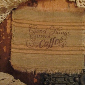 Peut inclure: Un tissu brun et beige avec un bord effiloché. Le tissu a un motif rayé et le texte "Good Things Happen Over Coffee" imprimé dessus.