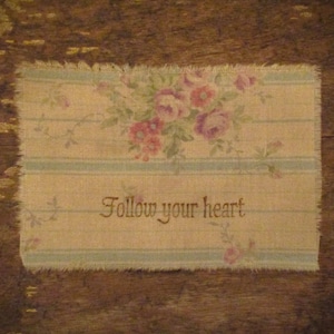 May include: A beige fabric with a floral pattern and the text "Follow your heart" printed on it.