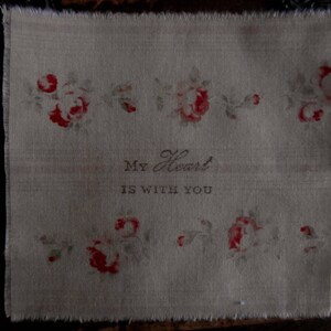 May include: A beige fabric with a floral pattern and the text "My Heart is With You".
