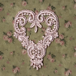 May include: A pink lace heart-shaped applique with intricate floral designs. This delicate embellishment is perfect for adding a touch of vintage charm to crafts and sewing projects.