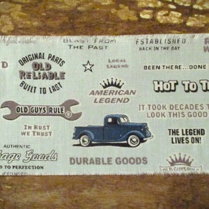 Könnte beinhalten: Ein Stoffdruck im Vintage-Stil mit einem blauen Pickup-Truck, einem Schraubenschlüssel und Text, der "Old Guys Rule", "Original Parts Old Reliable Built to Last", "American Legend", "Hot to Trot", "The Legend Lives On!" und "Durable Goods" lautet.