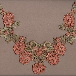 Könnte beinhalten: Eine zarte Spitzenborte mit einem floralen Muster in Grün- und Pfirsichtönen. Die Spitze weist komplizierte Details und einen gewellten Rand auf.