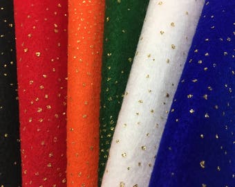 Puede incluir: Primer plano de varios rollos de tela de fieltro en varios colores, incluyendo negro, rojo, naranja, verde, blanco y azul. Cada rollo está salpicado de pequeños acentos de purpurina dorada, creando un efecto brillante. El fieltro parece suave y texturizado.