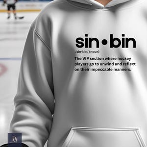 May include: White hoodie with a front pocket and a hood. The hoodie features the text "sin•bin" in a bold, black font, along with a definition that reads: "The VIP section where hockey players go to unwind and reflect on their impeccable manners."