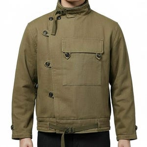 May include: Olive green jacket with a high collar, button closures, and a front pocket. The jacket features a belt at the waist and button details on the sleeves. The jacket is made of a durable fabric.